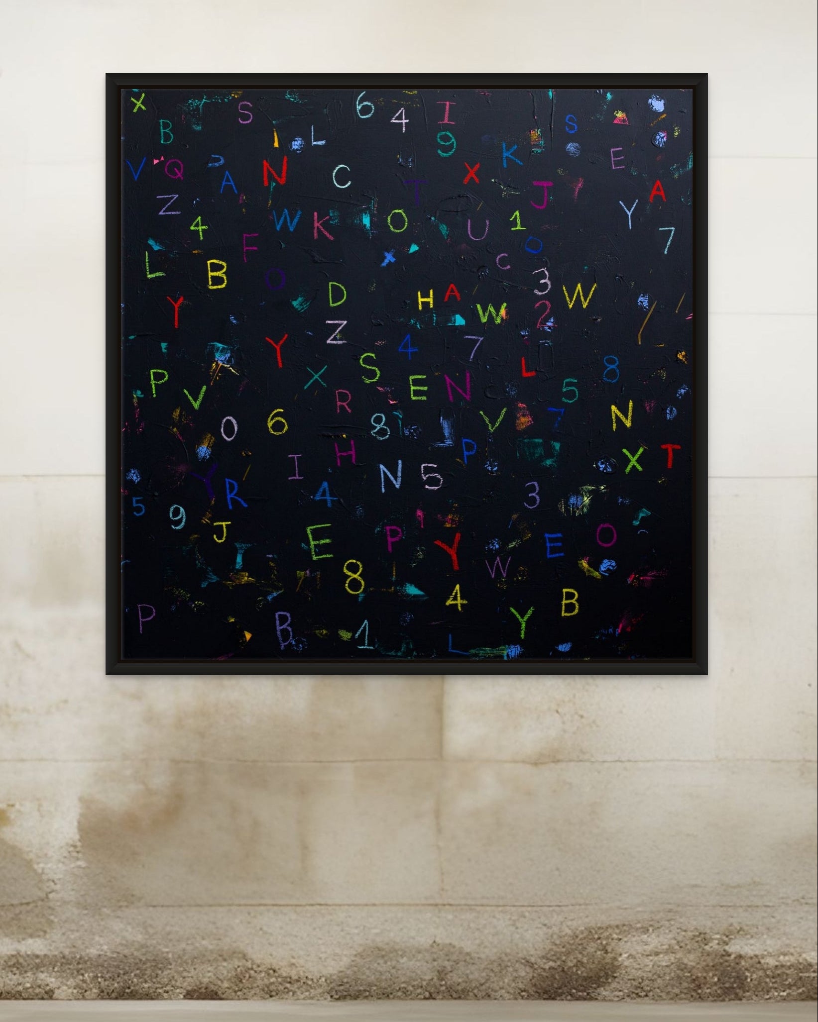 Framed artwork with colorful letters on a textured wall.