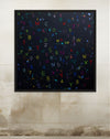 Framed artwork with colorful letters on a textured wall.